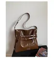 Detail of dark brown glossy shoulder bag with decorative straps and metallic D-rings - Brown