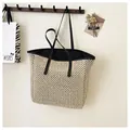 Detail of a woven straw tote bag with black leather straps hanging on a wall hook - One Size / Black