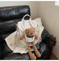 Chic beige backpack with teddy bear prints and plush charm on a leather sofa - With Pendant / Off White