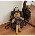 Brown backpack with bear prints and a plush teddy bear charm in a lifestyle interior setting - With Pendant / Coffee