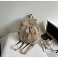 Detail of beige gingham backpack with plastic buckles on a bed near a laptop - Khaki
