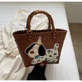 Detail of woven tote bag with natural bamboo handles and cartoon puppy patch embroidery - White Dog