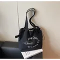 Dettaglio della borsa tote in tela nera con coulisse e stampa di lettere bianche - Taglia unica / Nero