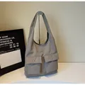 Detailansicht der grauen minimalistischen Tragetasche mit zwei Vordertaschen und Metallknöpfen - Einheitsgröße / Grau