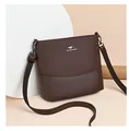 Close-up of brown textured bucket bag with metal kangaroo logo and canvas strap - Coffee