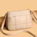 Detail of beige crossbody bag with litchi grain texture and golden kangaroo logo - One Size / Apricot
