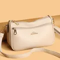 Macro detail of beige lychee grain leather crossbody bag and golden kangaroo logo - One Size / Beige