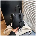 Detailed view of black lychee grain mini tote bag with cute dog charm and silver hardware - One Size / Black