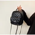 Detailed close-up of mini quilted backpack with sparkling crystal studs and chain strap - Black