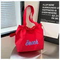 Vista de detalle del bolso de nailon rojo con cordón ajustable y estampado de Beach - Talla única / Rojo
