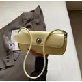 Detail of light yellow patent leather baguette bag featuring a silver metal twist lock - Yellow