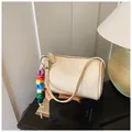 Chic beige cylinder crossbody bag with pebble leather texture and colorful bead charm - With Pendant / Off White