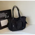Minimalist black canvas messenger bag with large front pocket and orange drawstrings - One Size / Black