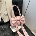 Sac à main rose avec un grand nœud orné de rivets argentés posé sur une chaise chic - Rose
