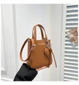 Detailed macro of brown lychee grain leather bucket bag with silver hardware and heart charm - One Size / Brown