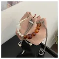 Detalle de bolso cubo mármol rosa con asa de perlas blancas y correa de cuentas ámbar - Talla única / Rosa