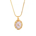 Detailed macro of gold oval pendant featuring letter K on a dainty snake chain necklace - Letter K
