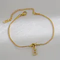 Detail van de gouden slangenarmband met knoop en zirkonia pavé letter B bedel hanger - Letter B