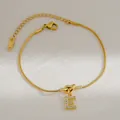 Detail van 18K vergulde slangenarmband met sprankelende hanger met de letter E - Letter E