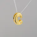 Vista macro del colgante de letra C burbuja 3D con un acabado dorado espejo pulido - Letra C