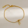 Detailopname van gouden letter F-hanger met zirkonia op een slangenketting armband - Letter F