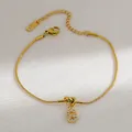 Detail van de gouden slangenschakelarmband met sprankelende letter G hanger en kristal - Letter G
