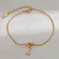 Macro-opname van de gouden slangenketting armband met sprankelende letter J hanger en knoopje - Letter J