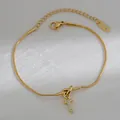 Detail van gouden slangenarmband met kristallen letter T-hanger en S925 zilveren stempel - Letter T