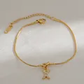 Detail van 18k vergulde slangenketting armband met knoopontwerp en zirkoon X-hanger - Letter X