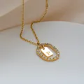 Dettaglio del ciondolo ovale dorato con micro-pave di cristalli e collana con lettera P - Lettera P