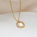 Dettaglio del pendente ovale dorato con zirconi brillanti e ciondolo con lettera V - Lettera V