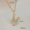 Detail of gold letter M pendant with cubic zirconia and specific size dimensions - M