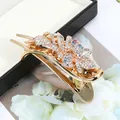Golden flower hair clip with sparkling rhinestones and elegant vine design on a black box - Multicolor Clover (Random)
