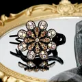 Pinza floral con cristales champán y pedrería AB sobre una base de resina negra - Champaña