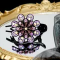 Elegante pinza de pelo floral con pedrería púrpura sobre un espejo vintage - Púrpura
