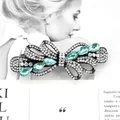 Elegant hollow bow hair clip with black metal base, white crystals, and blue rhinestones - Wisteria Green