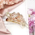 Elegant gold hair claw clip featuring champagne crystal flowers on a pink silk background - Champagne