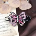 Elegant butterfly hair claw clip with pink crystals on a vintage musical background - Red