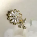 Elegante spilla a fiore dorata con cristalli di zircone bianchi su sfondo di raso beige - Forma di Fiore / Oro