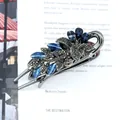 Gunmetal flower hair claw with navy crystals and grey rhinestones on a magazine - Campsis Grandiflora Blue