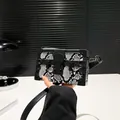 Fashionable box bag with snakeskin pattern, rivet details, and a metal clasp - Black