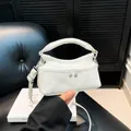 White denim mini square handbag with top handle and rivets, showing crossbody detail - White