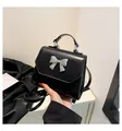 Detalle de mini bolso bandolera negro con lazo de metal plateado y textura lisa - Talla única / Negro
