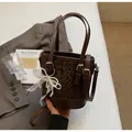 Dunkelbraune Eimer-Tasche mit Schlangenmuster, Perlen-Schleifen-Anhänger und Gurt - Mit Anhänger / Kaffeebraun