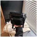 Gros plan sur un sac selle en similicuir noir avec fermetures éclair argentées - Noir