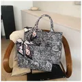 Detail shot of black and white paisley canvas tote bag with silk scarf on a wooden chair - Large / Black