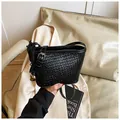 Women's black woven bucket bag with elegant crossbody strap shown on a beige blazer - With Pendant / Black