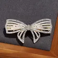 Elegante fermaglio per capelli a fiocco dorato con strass lucidi e perle bianche - Fiocco di Cristallo