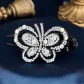 Elegant butterfly hair claw with sparkling AB crystals on a black base over blue satin - Double Butterfly White