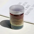 Coleteros elásticos multicolores en un bote cilíndrico transparente para el cabello - Colores Morandi